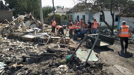 Des travailleurs communaux dégagent les débris d'une maison détruite le 25 août 2022, après la récente frappe aérienne russe dans la ville de Chaplyne, dans la région de Dnipro, en Ukraine. (STR / AFP)