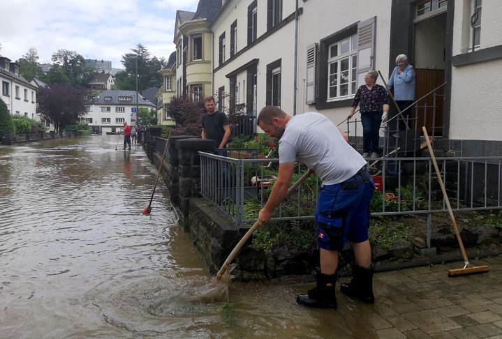 Des habitants de Mayen en Allemagne pompent l'eau de leur rue après des intempéries, le 15 juillet 2021. (MICHELLE FITZPATRICK / AFP)