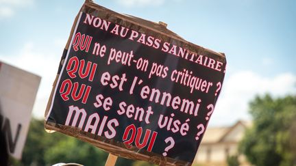 Une pancarte brandie lors de la manifestation anti-pass sanitaire le 14 août à Metz, reprennant la réthorique du "qui",&nbsp;devenue une référence discrète chez les militants antisémites. (NICOLAS BILLIAUX / HANS LUCAS VIA AFP)