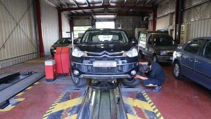 Un homme réalise un contrôle technique sur une voiture.&nbsp; (JEAN-FRAN?OIS FREY / MAXPPP)