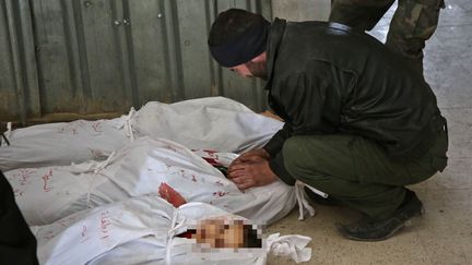 Un homme pleure près du corps d'une victime des bombardements qui visent la Ghouta orientale, près de Damas (Syrie), le 20 février 2018. (AMER ALMOHIBANY / AFP)