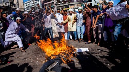 Des manifestants brûlent une effigie d'Emmanuel Macron lors d'une manifestation à Dacca (Bangladesh), le 30 octobre 2020. (MUSHFIQUL ALAM / NURPHOTO / AFP)