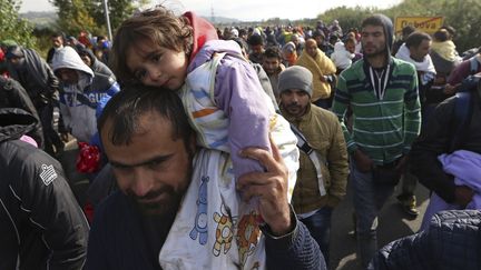 Un des migrants porte son enfant alors qu'il continue son voyage vers Dobov, en Slov&eacute;nie, le 20 octobre 2015. (? SRDJAN ZIVULOVIC / REUTERS )