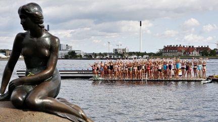 Derrière la Petite Sirène, cent filles d'apprêtent à plonger afin de célébrer le centième anniversaire du plus célèbre monument de Copenhague... (23 août 2013)
 (Nikolai Linares / Scanpix Danemark / AFP)