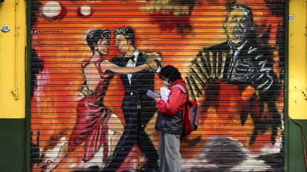 Un homme portant un masque devant un mural représentant des danseurs de tango à Buenos Aires, le 8 mai 2020.&nbsp; (RONALDO SCHEMIDT / AFP)