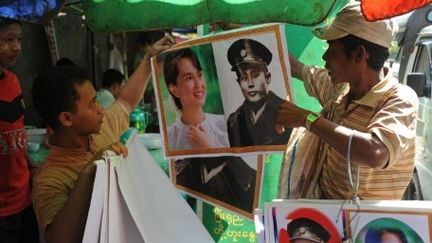 Un vendeur montrant, à Rangoun, des posters du héros de l'indépendance, Aung San, et de sa fille, Aung San Suu Kyi (13-12-2011) (AFP - Soe Than WIN)