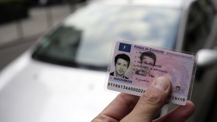 Un homme tient en main son permis de conduire le 11 septembre 2013 à Paris. (KENZO TRIBOUILLARD / AFP)