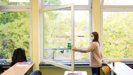 Une élève ouvre les fenêtres de sa classe à Hambourg (Allemagne), le 19 octobre 2020. (DANIEL BOCKWOLDT / DPA / AFP)