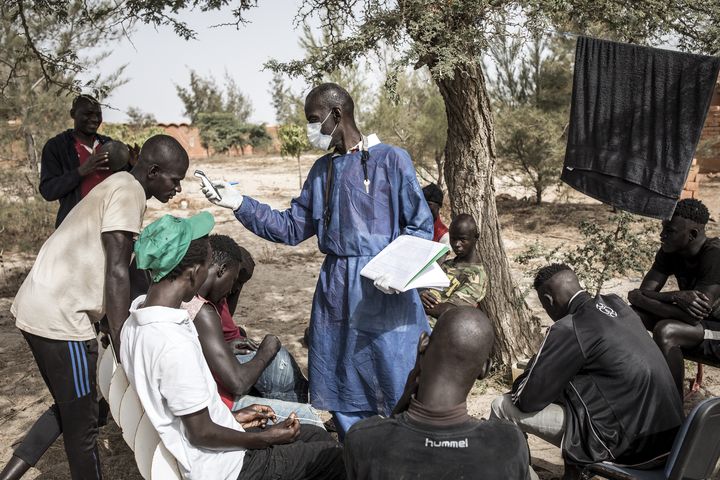 Un agent sanitaire prend la température de jeunes sans-abri, confinés en quarantaine, près de Dakar le 10 avril 2020.&nbsp; (JOHN WESSELS / AFP)