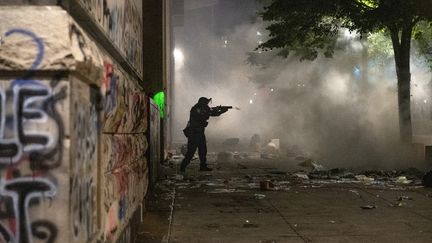 Un officier fédéral tire des gaz lacrymogènes sur une foule de manifestants à Portland, aux Etats-Unis, le 22 juillet 2020.&nbsp; (ZACH WILKINSON / SPUTNIK / AFP)