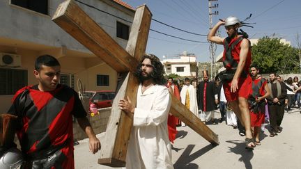 Un Chr&eacute;tien porte une croix en bois lors d'une procession dans le village libanais de Qraiyeh, le 3 avril 2015 pour le Vendredi saint. (MAHMOUD ZAYYAT / AFP)