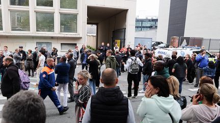 Des personnes se tiennent devant l'entrée du lycée Gambetta à Arras où une attaque au couteau a fait un mort et trois blessés, le 13 octobre 2023. (FRANCOIS LO PRESTI / AFP)