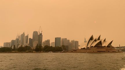 La brume des feux de brousse obscurcit le coucher du soleil au-dessus de l'Opéra de Sydney, le 6 décembre 2019.&nbsp;Les températures pourraient monter jusqu'à 47°C dans certaines parties de la Nouvelle-Galles du Sud. La capitale devrait avoir des températures un peu plus clémentes, autour de 37°C.&nbsp;
 (JOHN MAIR / REUTERS)