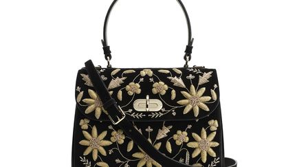 Avec sa fermeture à tourniquet et son cadenas assorti, le Tiffin, sac emblématique de la maison Ralph Lauren, affiche un style élégant dans cette version en suède noir recouvert d’une composition florale brodée à la main de fils dorés. Un seul et même artisan développe chaque modèle afin de maintenir la cohérence du motif. Il décline toute une variété de points pour dessiner les feuilles et les fleurs. Deux semaines sont nécessaires pour concevoir les panneaux qui forment le sac.
 (Ralph Lauren)