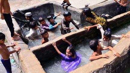 Des enfants pakistanais se rafraîchissent dans un lavoir, dans la&nbsp;province du Sindh (sud du Pakistan), où le thermomètre approche les 50 degrés, le 14 mai 2022.&nbsp; (SHAKEEL AHMED / ANADOLU AGENCY / AFP)