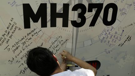 Un homme &eacute;crit un message sur un panneau en m&eacute;moire des disparus du vol MH370, le 8 mars 2015, &agrave; Kuala Lumpur (Malaysie). (AHMAD YUSNI / NURPHOTO / AFP)