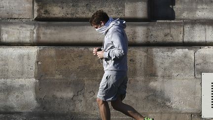 Un joggeur, visage masqué dans le centre de Paris le 8 avril 2020. (ALAIN JOCARD / AFP)