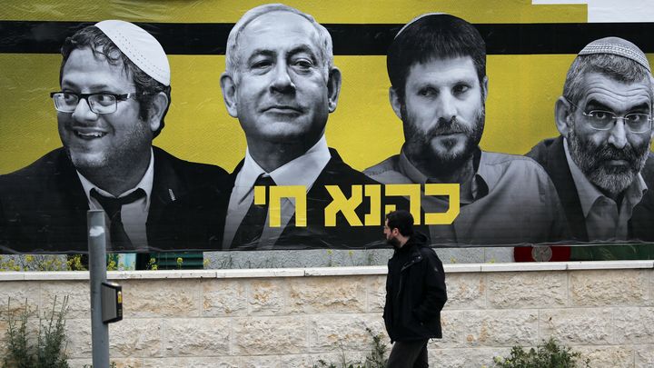 Un homme passe devant une affiche électorale  montrant le Premier ministre israélien Benyamin Netanyahou, Itamar Ben Gvir (à gauche), Bezalel Smotrich et Michael Ben Ari (à droite), à Jérusalem, le 29 mars 2019. (THOMAS COEX / AFP)