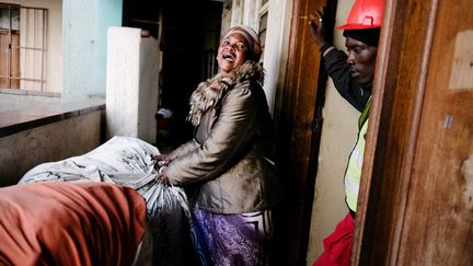 une squatteuse zimbabwéenne est délogée manu militari par un membre des Fourmis rouges. Ces groupes d'intervention musclée, mandatés par les propriétaires d'immeubles, débarquent dans les appartements occupés illégalement, armés de fusils et de pieds de biche. Ils jouent la carte de l'intimidation et n'hésitent pas à mettre sur le trottoir ou à jeter par la fenêtre les biens des occupants. C'est la double peine pour ces résidents mal logés, escroqués par des gangs de malfaiteurs qui perçoivent les loyers à la place des propriétaires. (MARCO LONGARI / AFP)