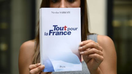 Une femme tient un exemplaire du livre de Nicolas Sarkozy, "Tout pour la France", qui va paraître mercredi 24 août 2016.&nbsp; (BERTRAND GUAY / AFP)