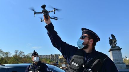 Des policiers déploient un drone au pied de la Tour Eiffel, à Paris, le 8 avril 2020. (ANTOINE LORGNIER / ONLY FRANCE / AFP)