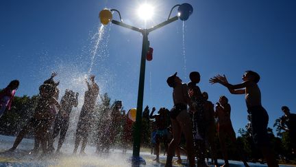 Des enfants se rafraîchissent sous des douches pendant la canicule. Photo d'illustration. (PATRICK HERTZOG / AFP)