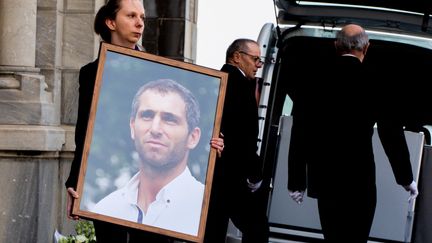 Une femme tient le portrait de l'ancien joueur de rugby Federico Martin Aramburu lors de son enterrement à Biarritz (Pyrénées-Atlantiques), le 26 mars 2022. (THIBAULT SOUNY / AFP)