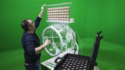 Un employé de la Française des jeux installe les boules de l'Euromillions dans le studio d'enregistrement de l'entreprise, à Boulogne-Billancourt, le 9 avril 2018. (JOEL SAGET / AFP)