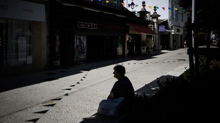 Une personne assise à l'ombre dans une rue de Montélimar (Drôme) le 22 août 2023. (JEFF PACHOUD / AFP)