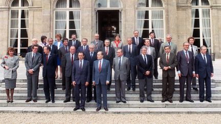 François Mitterrand et son Premier ministre Michel Rocard, le 13 mai 1988, à l'Elysée à Paris, entourés des ministres du gouvernement. (PATRICK HERTZOG / AFP)