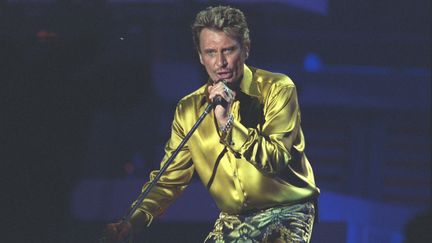 Tout en jaune or, Johnny Hallyday chante sur le Champs de Mars, à Paris, le 10 juin 2000. (JEREMY BEMBARON / SYGMA / GETTY IMAGES)