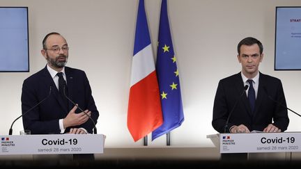 Edouard Philippe, alors Premier ministre, et Olivier Véran, le ministre de la Santé, lors d'une conférence de presse à Paris, le 28 mars 2020. (GEOFFROY VAN DER HASSELT / AFP)