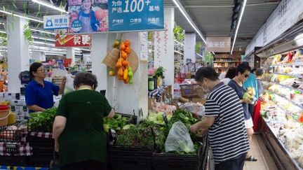 Des personnes choisissent leurs fruits dans un supermarché de Shanghai (Chine), le 2 août 2024. (YING TANG / NURPHOTO / AFP)