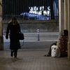 Une passante marche devant une personne sans-abri, le 8 janvier 2024 à Paris, près du jardin des Tuileries. (ALAIN JOCARD / AFP)