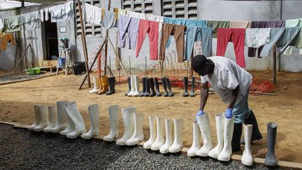 &nbsp; (Un infirmier libérien procède à la désinfection des bottes des personnels soignants à l'extérieur d'un centre de traitement d'Ebola, à Monrovia  © Maxppp)