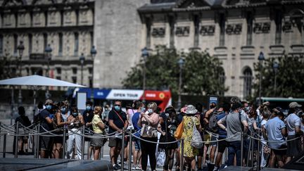 Des personnes portent un masque&nbsp;dans la file d'attente pour entrer au musée du Louvre, le 6 août 2020, à Paris. (STEPHANE DE SAKUTIN / AFP)