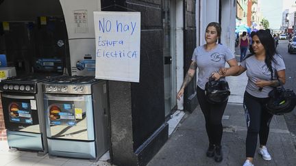 Deux personnes à côté d'un signe expliquant qu'il "n'y a pas de four électrique" dans un magasin d'électroménager à Cali (Colombie), alors qu'une coupure de gaz géante est en cours, le 24 mai 2023. (JOAQUIN SARMIENTO / AFP)