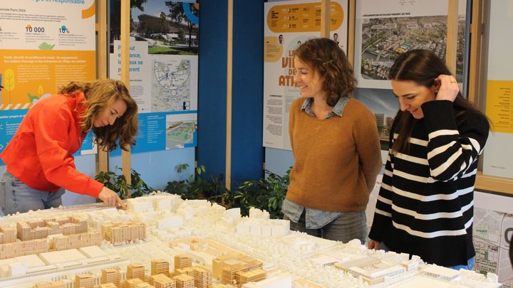 Julia Watson, adjointe au directeur de projet du village des athlètes à la Solideo, présente la maquette du village olympique aux escrimeuses, Pauline Ranvier (à gauche) et Charlotte Lembach (à droite), venues visiter le site, le 10 mars 2023. (APOLLINE MERLE / FRANCEINFO: SPORT)