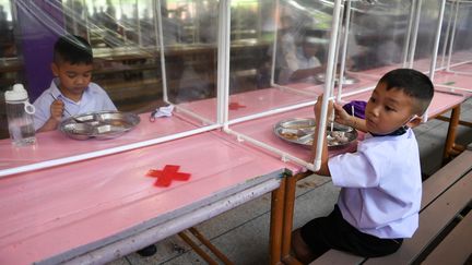 Des enfants à l'école en Thaïlande déjeunent derrière des protections en plastique, le 1er juillet 2020. (CHALINEE THIRASUPA / REUTERS)