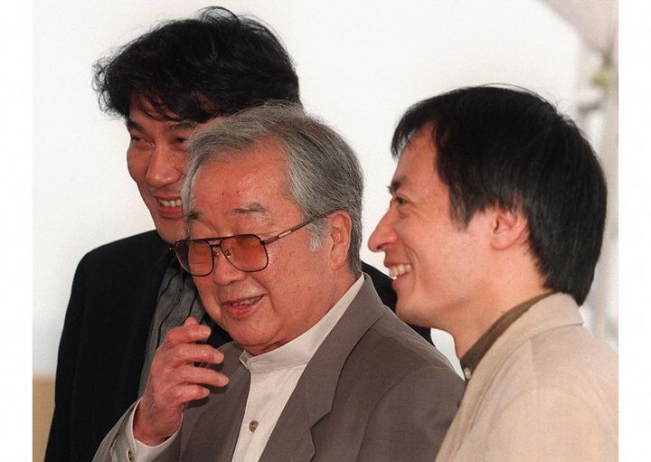 Japanese director Shohei Imamura, center, poses for photographers with actor Koji Yakusho, left, and an unidentified producer May 12, 1997 during the presentation of their film 