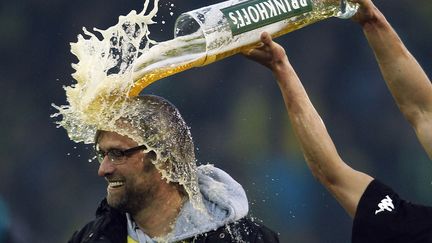 Lukasz Piszczek (D) du Borussia Dortmund verse de la bi&egrave;re sur son entra&icirc;neur Juergen Klopp apr&egrave;s avoir remport&eacute; le titre de champion d'Allemagne &agrave; Dortmund, le 21 avril 2012. (INA FASSBENDER / REUTERS)