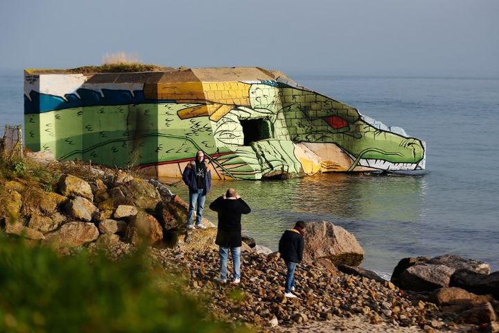 Des touristes devant le dragon "Shenron" de Dragon Ball, peint sur un blockhaus, de la plage de Réville (Manche)
 (CHARLY TRIBALLEAU / AFP)