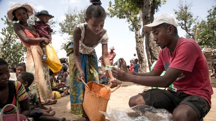 Un travailleur humanitaire de l'ONG Action contre la faim distribue des compléments alimentaires dans la commune d'Ifotaka, dans le sud de Madagascar, le 14 décembre 2018. (RIJASOLO / AFP)