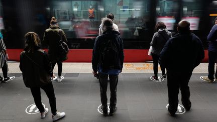 Des voyageurs attendent sur un quai de tramway, en respectant les repères peints au sol,&nbsp;le 11 mai 2020 à Nice (Alpes-Maritimes). (VALERY HACHE / AFP)