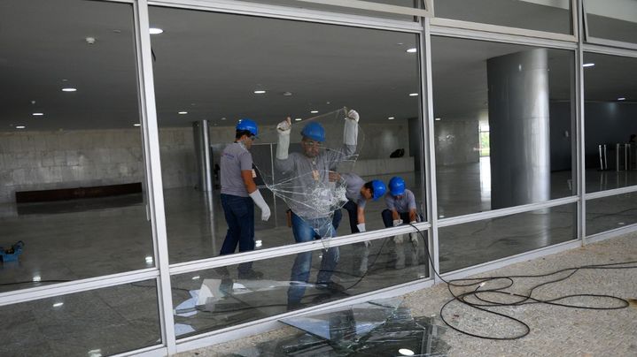 Des ouvriers s'affairent pour réparer une vitre du palais présidentiel, à Brasilia, le 9 janvier 2023. (MAURO PIMENTEL / AFP)