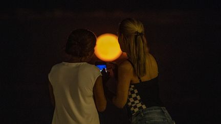 Deux femmes prennent en photo la "super lune" à Revere, dans l'Etat du Massachusetts&nbsp;(Etats-Unis). (JOSEPH PREZIOSO / ANADOLU AGENCY / AFP)