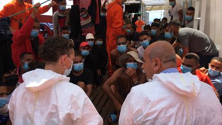 Un médecin italien (à droite) fait face à des migrants secourus sur le navire humanitaire "Ocean Viking", en Méditerranée, le 4 juillet 2020. (SHAHZAD ABDUL / AFP)