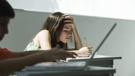 Des enfants sont en train d'écrire soit sur ordinateur soit avec un stylo.
 (MAXPPP)