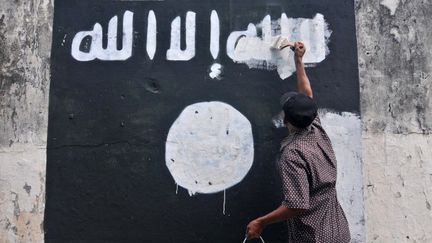 Un employé de la voirie efface un drapeau de l'Etat islamique peint sur un mur de la ville de Surakarta dans la province de Java en Indonésie.  (AFP/ Citizensside/ Agoes Rudianto)