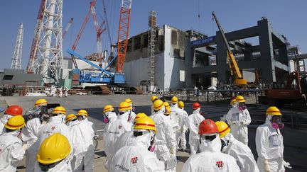 Des employ&eacute;s de la compagnie&nbsp;Tepco inspectent le b&acirc;timent du r&eacute;acteur n&deg;4 de la centrale de Fukushima, le 6 mars 2013. (ISSEI KATO / GETTY IMAGES)